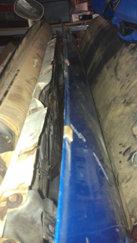 1973 Chevrolet Camaro - A blue car door is stored among other parts, showing signs of wear and tear.