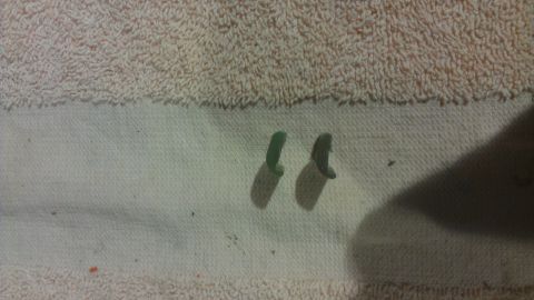 1973 Chevrolet Camaro - Two small green plastic clips are shown on a white cloth surface.