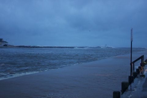 1990 Ford Bronco - A coastal scene shows flooding and rough seas, with a building on the left and a signpost on the right.