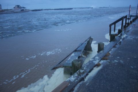 1990 Ford Bronco - Ocean waves crash over a flooded boardwalk, carrying debris during a storm.