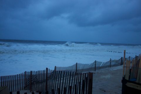 1990 Ford Bronco - A beach scene during a storm with rough waves and a damaged wooden fence.