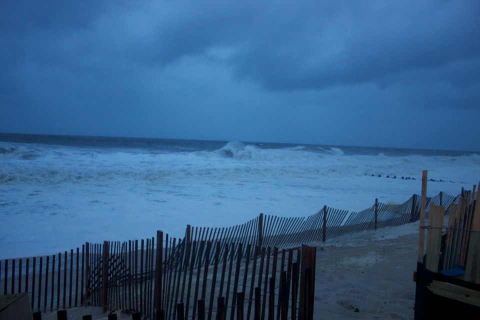 Stormy beach with large waves crashing and a wooden fence