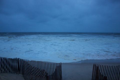 1990 Ford Bronco - A desolate beach scene with a wooden fence and rough ocean waves under a stormy sky.