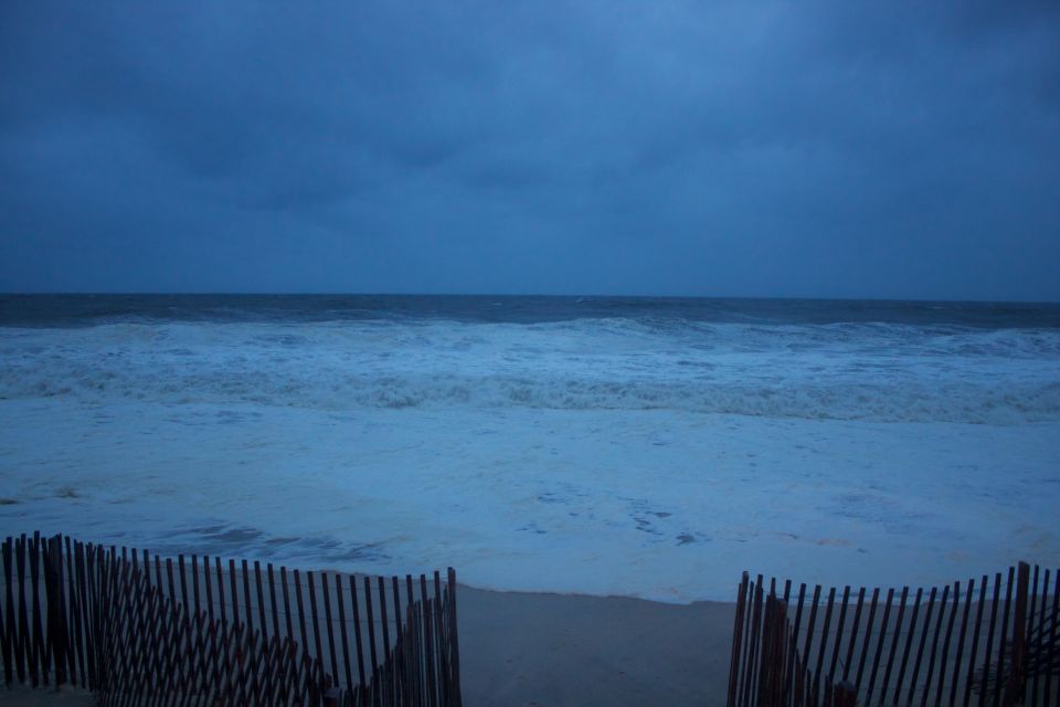 Beach scene with fence and choppy ocean under a cloudy sky