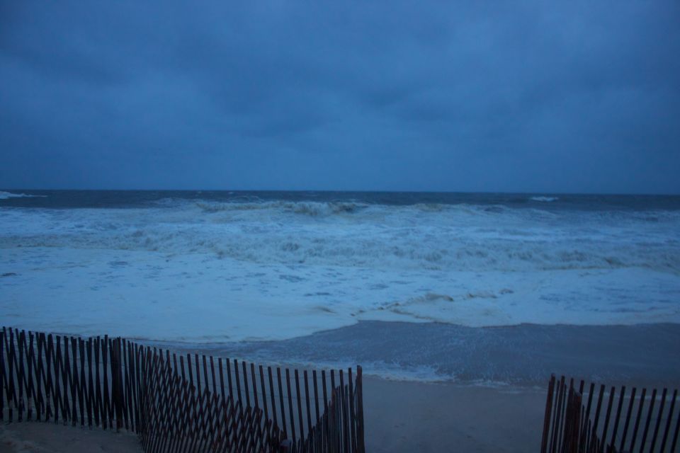 Stormy ocean waves and beach with a wooden fence
