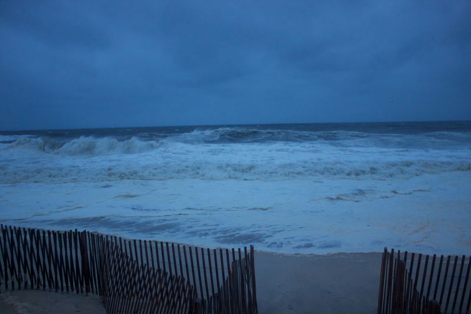 Beach fence with stormy ocean waves under a dark blue sky