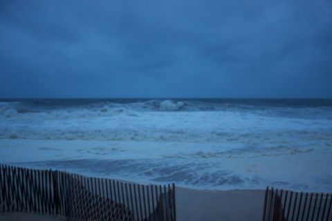 1990 Ford Bronco - Rough seas and overcast skies suggest a storm at the beach, with a wooden fence in the foreground.
