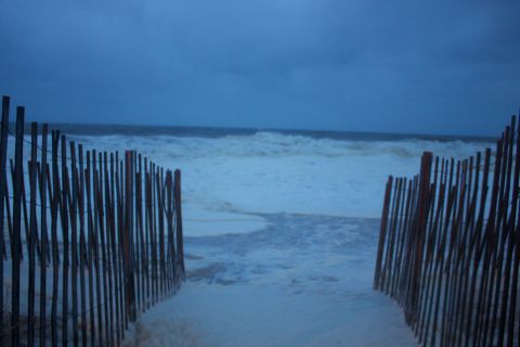 1990 Ford Bronco - A beach scene with a wooden fence and rough ocean waves under a dark sky.