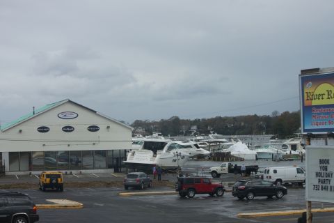 1990 Ford Bronco - A yellow SUV is parked in a lot near a building and several boats docked at a marina.