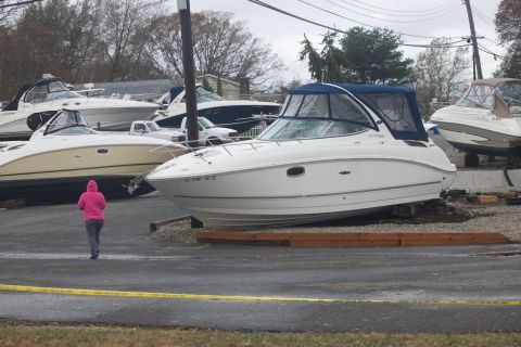 1990 Ford Bronco - Boats are stored on land, possibly after a storm, with a person walking by.