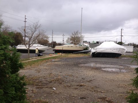 1990 Ford Bronco - Boats are parked on a gravel lot after a storm, with one boat covered and others exposed.