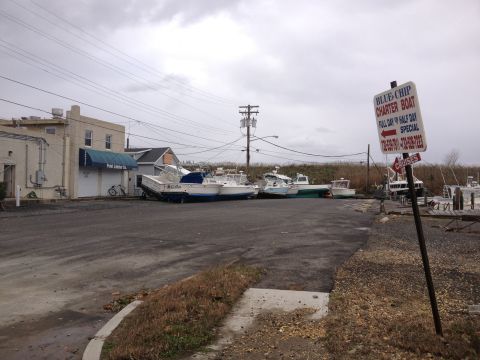1990 Ford Bronco - Boats are parked on a lot near buildings, with a charter boat sign visible.