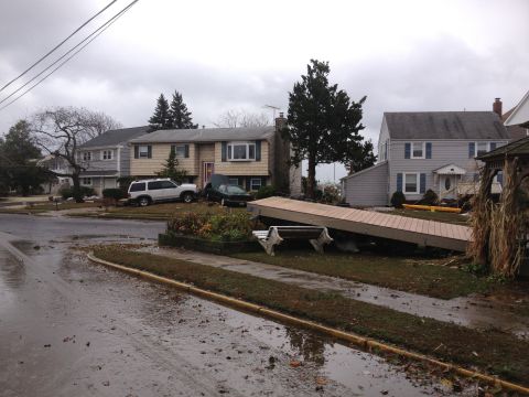 1990 Ford Bronco - Suburban neighborhood shows damage from a storm, with two vehicles partially submerged in water.