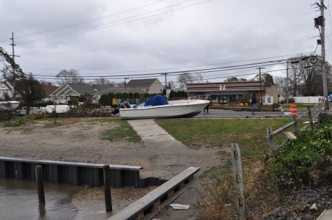 1990 Ford Bronco - A boat sits on land, displaced from the water, with a 7-Eleven store in the background.