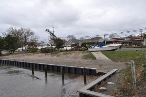 1990 Ford Bronco - A boat sits on land near a damaged shoreline and trees, with a 7-Eleven store in the background.