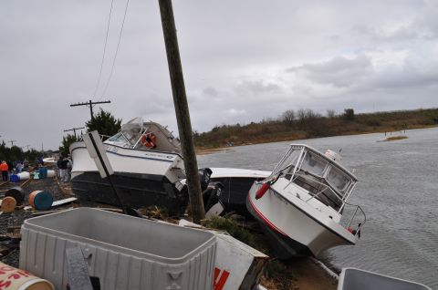 1990 Ford Bronco - Boats washed ashore and damaged by flooding, with debris scattered around the scene.