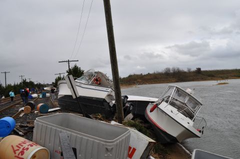1990 Ford Bronco - Boats and debris litter train tracks after a storm, indicating significant flooding and damage.
