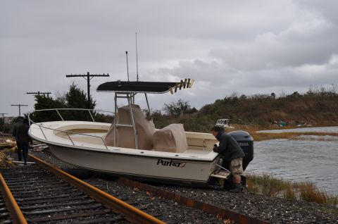 1990 Ford Bronco - A boat has been moved onto train tracks next to a body of water under a cloudy sky.