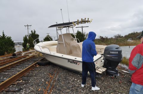 1990 Ford Bronco - A boat sits stranded on train tracks near a body of water under a cloudy sky.