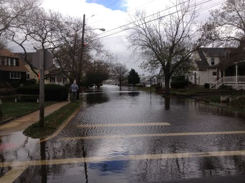 1990 Ford Bronco - A street is submerged in floodwaters, with houses lining the sides.
