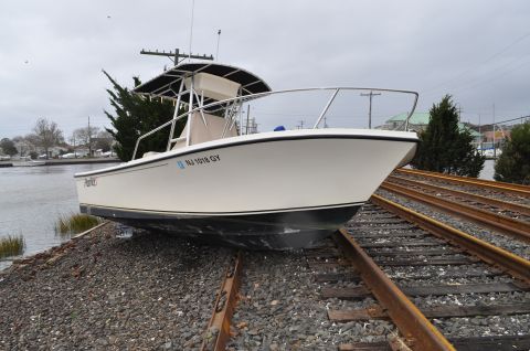 1990 Ford Bronco - A boat sits stranded on train tracks, a peculiar sight against a backdrop of water and trees.