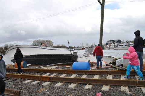1990 Ford Bronco - Boats washed ashore and resting on train tracks, indicating significant storm damage.