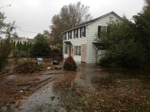1990 Ford Bronco - A house and yard are submerged in floodwaters, with debris scattered around the scene.