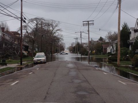 1990 Ford Bronco - A flooded street in a residential area after a storm, with several vehicles partially submerged.