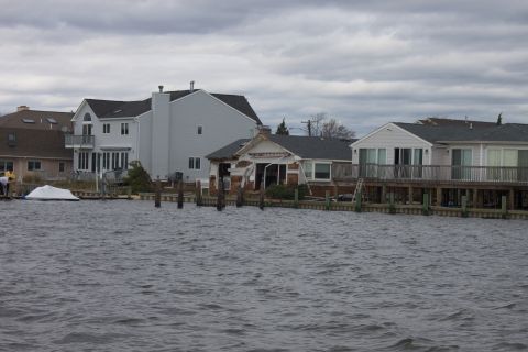 1990 Ford Bronco - Waterfront homes show damage from flooding under a gray, overcast sky.