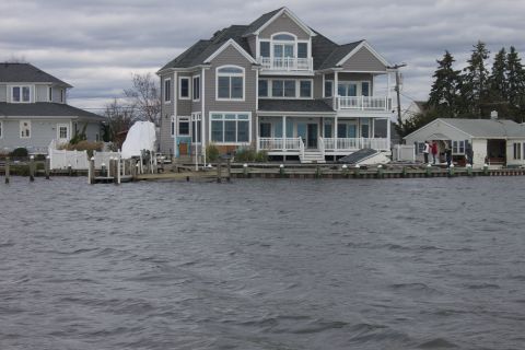 1990 Ford Bronco - Houses line a waterfront with choppy water in the foreground under an overcast sky.