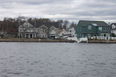 1990 Ford Bronco - Houses line the waterfront under a cloudy sky, with water in the foreground.