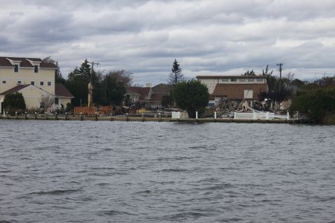 1990 Ford Bronco - Waterfront properties show significant damage after a severe storm, with debris visible along the shoreline.