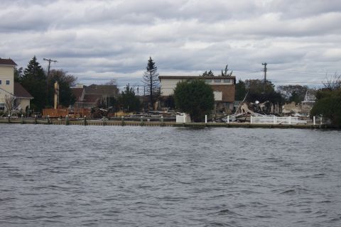 1990 Ford Bronco - A waterfront scene shows the aftermath of a storm with damaged buildings and debris scattered along the shore.
