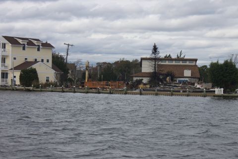 1990 Ford Bronco - A waterfront scene shows damaged buildings and debris, likely from Hurricane Sandy, under an overcast sky.