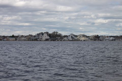 1990 Ford Bronco - A waterfront view shows houses lining the shore under a heavily clouded sky.