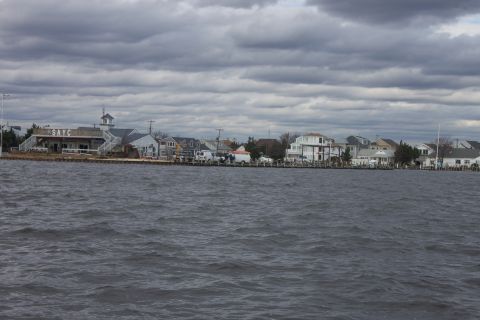 1990 Ford Bronco - A waterfront scene with houses and a building marked SAYC under a dramatic, cloudy sky.