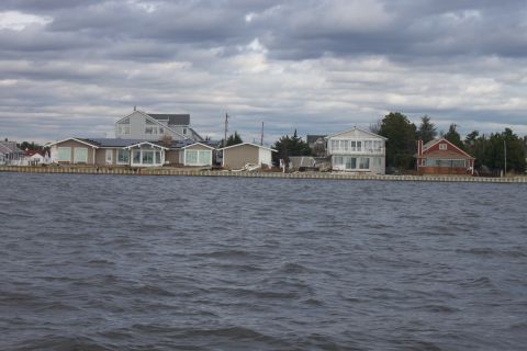 1990 Ford Bronco - Houses line the waterfront under a dramatic, cloudy sky.