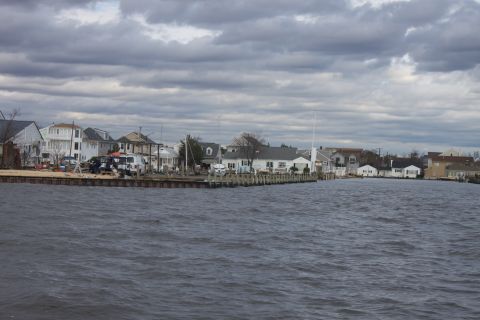 1990 Ford Bronco - A waterfront scene with houses lining the shore under a dramatic, cloudy sky.