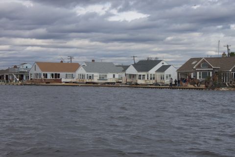 1990 Ford Bronco - Houses stand partially submerged in water following a storm, with a cloudy sky overhead.