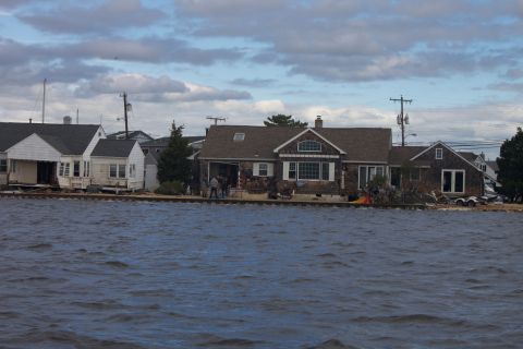 1990 Ford Bronco - Waterfront homes show damage from flooding under a cloudy sky.