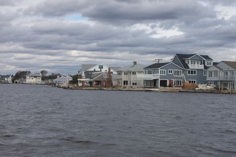 1990 Ford Bronco - A view of waterfront homes showing damage from Hurricane Sandy, with a boat partially submerged near the shore.