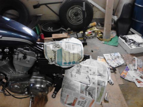 2003 Harley-Davidson Sportster - A motorcycle's engine and fuel tank are partially visible in a messy garage setting, surrounded by various items.