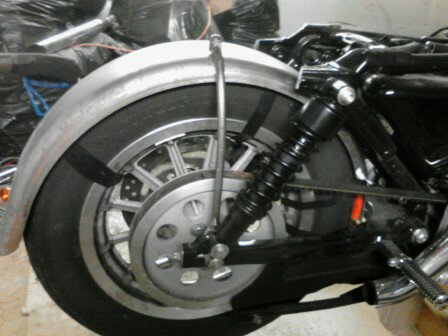 2003 Harley-Davidson Sportster - Close-up view of the rear wheel, fender, and shock absorber assembly on a motorcycle.