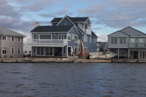 1990 Ford Bronco - A boat lies on the sand near waterfront homes that show signs of storm damage.
