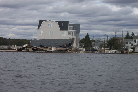 1990 Ford Bronco - Waterfront properties show significant damage from a storm, with debris scattered and structures compromised.