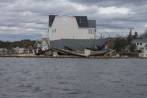 1990 Ford Bronco - A house and its deck are severely damaged by a storm, with debris scattered around the property.