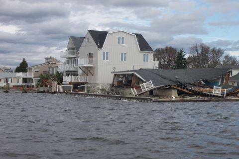 1990 Ford Bronco - Houses damaged by flooding and storm surge, with debris scattered and a roof caved in.
