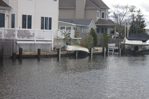 1990 Ford Bronco - A canal runs past waterfront homes, with a small dinghy and a larger covered boat docked.