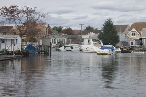 1990 Ford Bronco - Boats are seen docked in a flooded residential area, with some partially submerged, under an overcast sky.