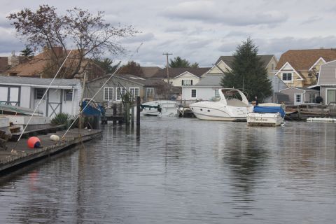 1990 Ford Bronco - A scene of flooded residential area with boats moored along a dock, under a cloudy sky.